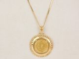 a gold necklace with a coin on a mannequin neck