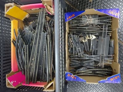 two boxes of train tracks sitting on a metal table