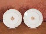deux assiettes blanches ornées de motifs dorés et bleus, posées sur une table
