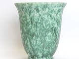 a green vase that is sitting on a white surface
