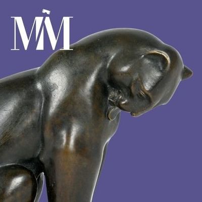 une statue en bronze représentant un chat assis sur une table