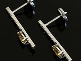 two pairs of silver and gold earrings on a black surface