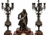 une statue représentant un homme assis sur une table, à côté de trois chandeliers