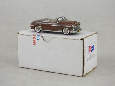 une petite voiture jouet marron posée sur une boîte