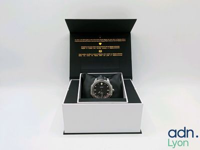 une image représentant une montre dans un écrin noir posé sur une surface blanche