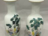 une paire de vases chinois ornés de scènes asiatiques, posés sur une surface blanche
