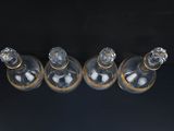 four empty glass bottles sitting on top of a black surface
