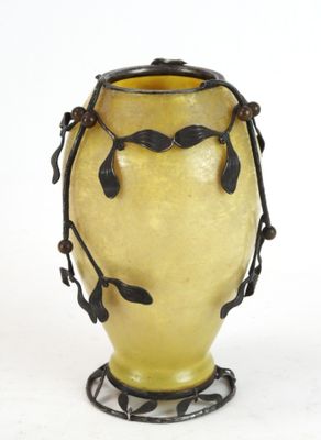 un vase jaune orné de feuilles noires, posé sur un socle