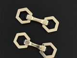 une paire de pinces hexagonales plaquées laiton sur fond noir