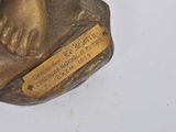 a bronze statue of a dog with a tag on it