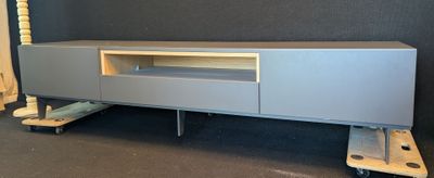 a grey entertainment center with wheels and a tv on it