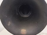 a black speaker on a metal stand on a white surface