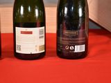three bottles of wine sitting on a red cloth