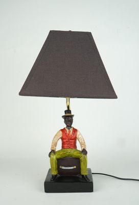 une figurine représentant un homme assis sur une chaise sur laquelle est posée une lampe
