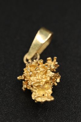 un gros plan d'un pendentif en forme de fleur dorée sur une surface noire