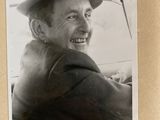 black and white photograph of a man in a hat sitting in a car