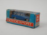 une petite voiture bleue dans une boîte posée sur une surface blanche