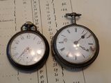 deux vieilles montres de poche posées sur un morceau de papier