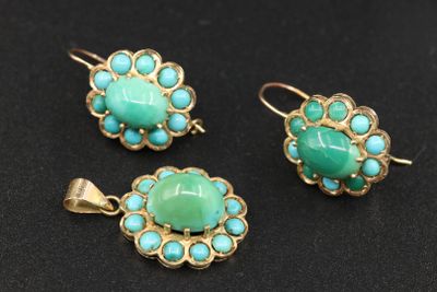 trois bijoux en turquoise et or posés sur un fond noir