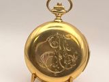 une montre de poche en or posée sur un socle, sur fond blanc