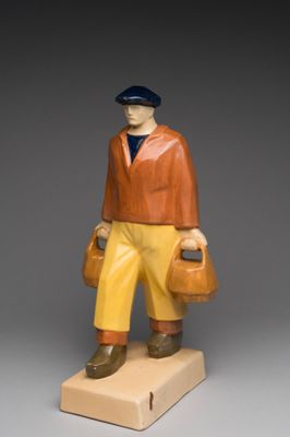 figurine of a man with a hat, jacket, and yellow pants holding a bag