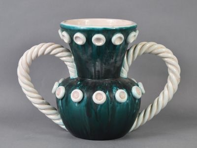 un vase vert et blanc muni d'une anse en corde