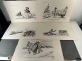 Plusieurs dessins représentant des personnes sont posés sur une table dans une pièce.