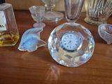bottles of perfume and a clock sitting on a table next to a bottle of perfume