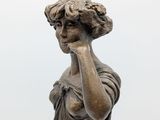 statue of a woman holding a lamp on a pole on a white background