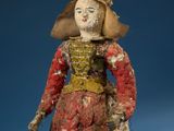 an old doll with a red dress and hat on a blue background