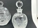 pair of clear glass perfume bottles on a black surface