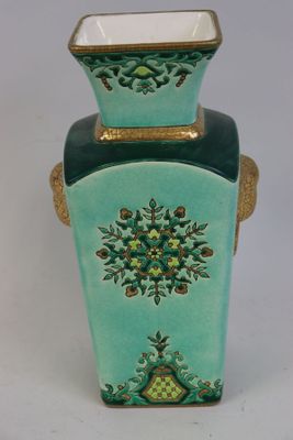 un vase vert avec une anse dorée sur fond blanc