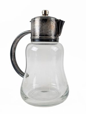 a glass pitcher with a metal lid on a white background