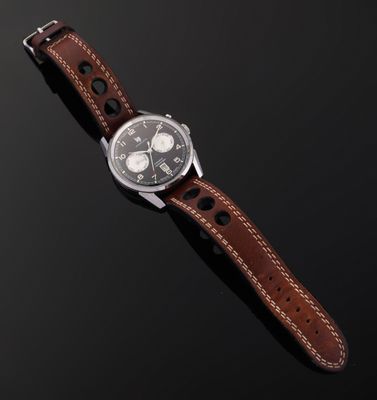 a watch with a brown leather strap sitting on top of a black surface