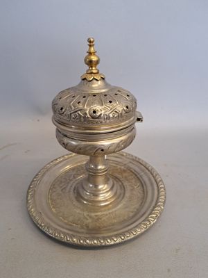 an antique silver plate with a lid on a white surface