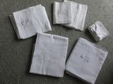quatre serviettes blanches ornées de monogrammes brodés, posées sur une table