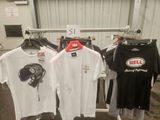 Plusieurs t-shirts sont suspendus à un portant dans un garage.