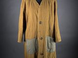 une photo d'un manteau posé sur un pied de mannequin, sur fond noir