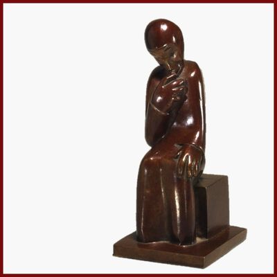 statue d'une femme assise sur un bloc, la main posée sur la poitrine