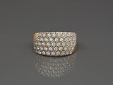 un gros plan d'une bague en or et diamants posée sur une surface réfléchissante