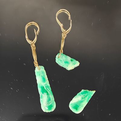 trois boucles d'oreilles en jade vert et or sur un fond noir