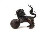 bronze figurine of a dog playing with a ball on a white background