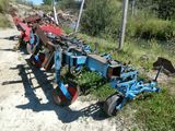 une charrue bleue garée au bord d'un chemin de terre