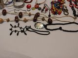 many different necklaces and bracelets laid out on a table