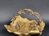 plaque en laiton ornée de feuilles et de fleurs, posée sur un fond noir