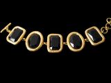 a close up of a black and gold necklace on a black background