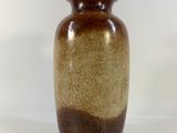 un grand vase marron posé sur une surface blanche