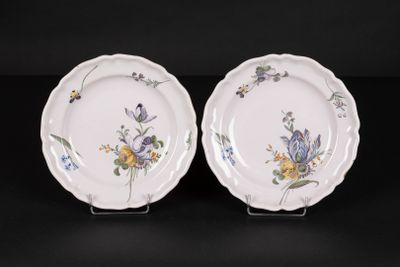 two plates with floral designs on them sitting on a black surface