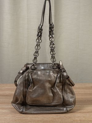 leather handbag on a wooden table with a curtain in the background