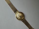 a close up of a gold watch on a white surface